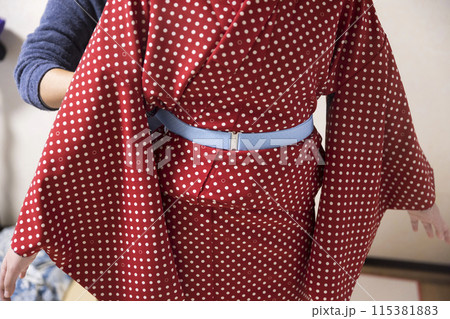 着物着付けイメージ　コーリンベルトを巻いてもらう女性 115381883