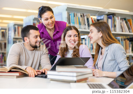 Group of friendly students working on joint research in library 115382304