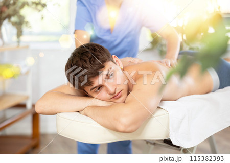 Female massagist doing massage to male client in spa center 115382393