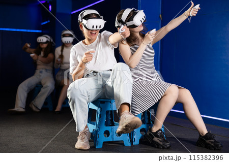 Female friends playing pair versus pair virtual reality game 115382396