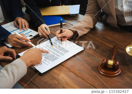 Lawyer signing important legal document on desk at office. 115382427