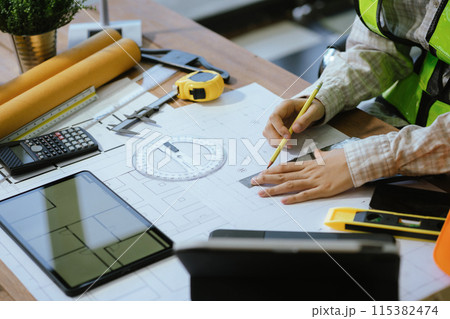 Person's engineer Hand Drawing Plan On Blue Print with architect equipment, Architects discussing at the table, team work and work flow construction concept. 115382474