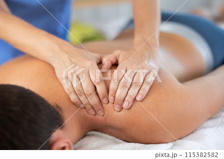 Masseuse doing back massage to young guy 115382582