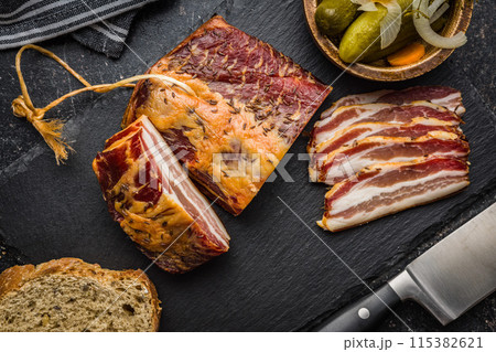 Closeup of Sliced Smoked Bacon on Black Slate Cutting Board. Top view. Closeup of Sliced Smoked Bacon on Black Slate Cutting Board. Top view. 115382621