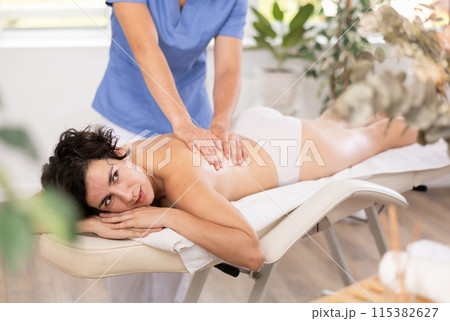 Portrait of woman relaxing on massage table at spa center Portrait of woman relaxing on massage table at spa center 115382627