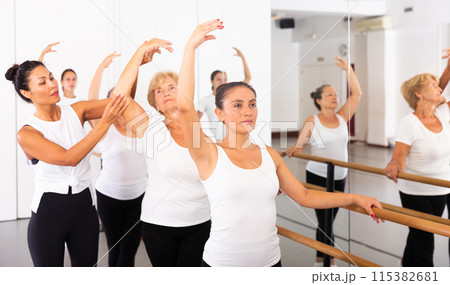 Dancing women stand in a ballet stance, where the choreographer helps to coordinate the movement Dancing women stand in a ballet stance, where the choreographer helps to coordinate the movement 115382681