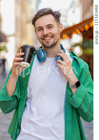 Happy man enjoying morning coffee hot drink and smiling relaxing, taking a break on city street Happy man enjoying morning coffee hot drink and smiling relaxing, taking a break on city street 115383466