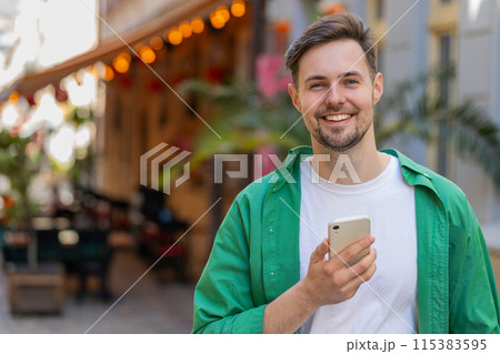 Man using smartphone typing text messages browsing internet, finishing work, looking at camera Man using smartphone typing text messages browsing internet, finishing work, looking at camera 115383595