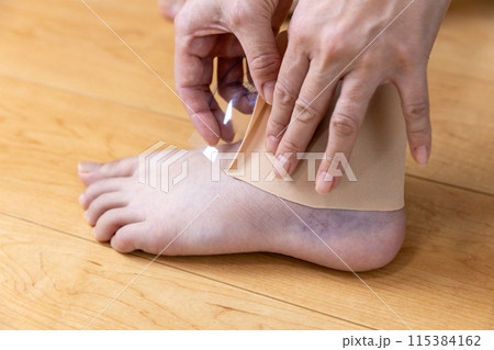 ねん挫した足首に湿布を貼る女性 115384162