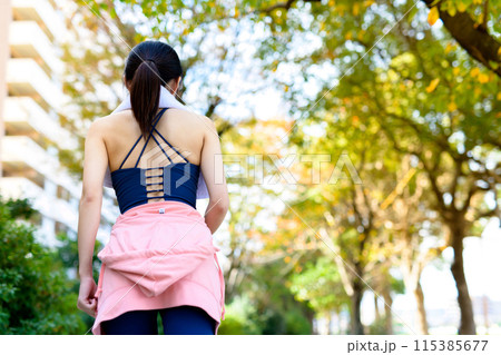 秋の公園の街路樹の道をジョギングする若い女性の後ろ姿 ダイエット ボディメイク 秋の公園の街路樹の道をジョギングする若い女性の後ろ姿 ダイエット ボディメイク 115385677
