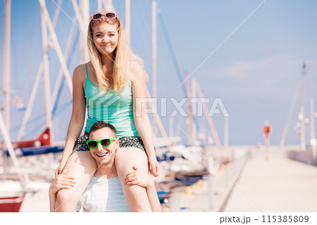 Man giving girlfriend piggyback ride on marina Man giving girlfriend piggyback ride on marina 115385809