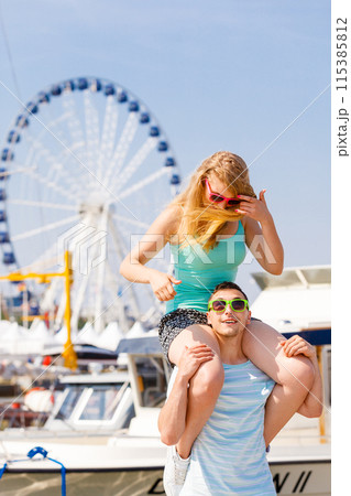Man giving girlfriend piggyback ride on marina Man giving girlfriend piggyback ride on marina 115385812