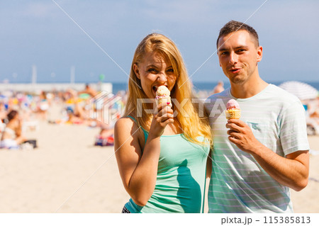 Man and woman eating ice cream on beach 115385813