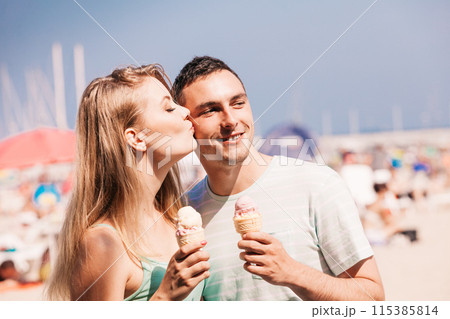 Man and woman eating ice cream on beach 115385814