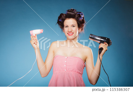 girl with curlers in hair holds hairdreyers 115386307