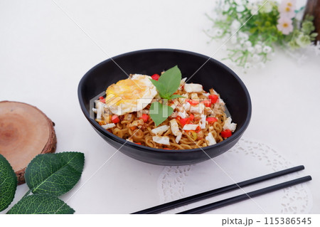 fried noodles with fried egg and vegetables as a background 115386545