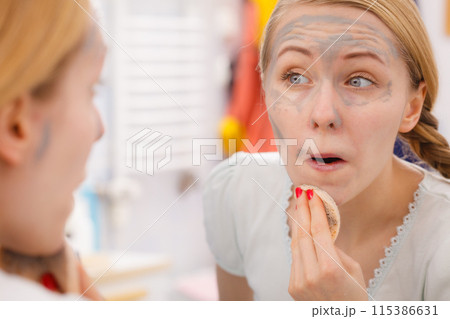 Woman removing mud facial mask with sponge Woman removing mud facial mask with sponge 115386631