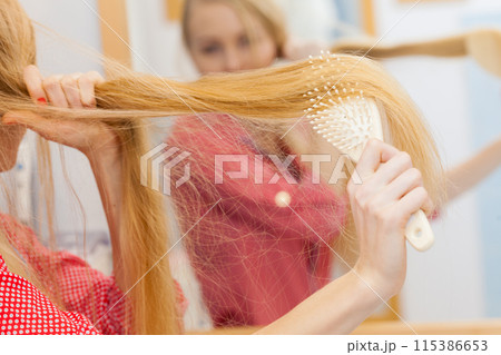 Woman brushing her long hair in bathroom 115386653