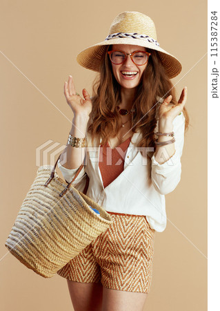 happy elegant woman in blouse and shorts against beige happy elegant woman in blouse and shorts against beige 115387284
