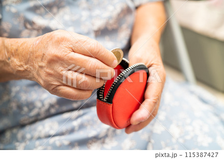 Asian senior woman holding counting coin money in purse. Poverty, saving problem in retirement. 115387427