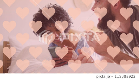 Image of hearts over happy diverse couple using smartphone Image of hearts over happy diverse couple using smartphone 115388922