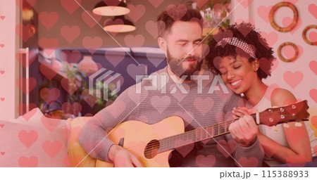 Image of hearts over happy diverse couple playing guitar 115388933