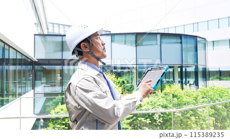 タブレットを見ながら建物をチェックするエンジニア 115389235