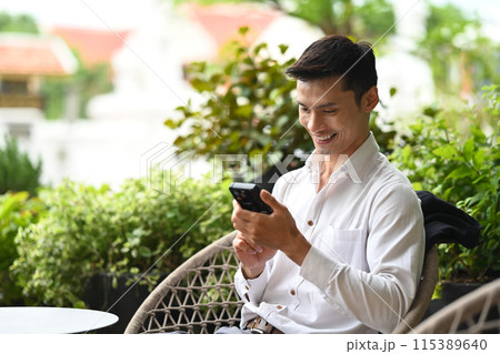 Smiling businessman using mobile phone on cafe terrace Smiling businessman using mobile phone on cafe terrace 115389640