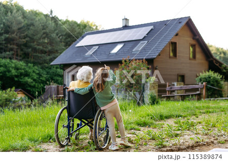 Granddaughter spending time with elderly grandma, companionship. Senior lady in wheelchair spending time in nature. Granddaughter spending time with elderly grandma, companionship. Senior lady in wheelchair spending time in nature. 115389874