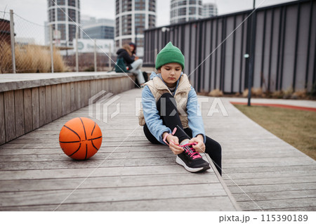 Girl in the city going to play basketball. Young girl spending free time doing sport, enjoying after schoold outdoor activity. Girl in the city going to play basketball. Young girl spending free time doing sport, enjoying after schoold outdoor activity. 115390189