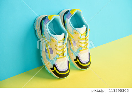 White sneakers with colored accents on bright background, Pair of fashionable sport shoes with colorful backdrop. Studio shot of shoes for shop advertisement, creative minimalist style 115390306