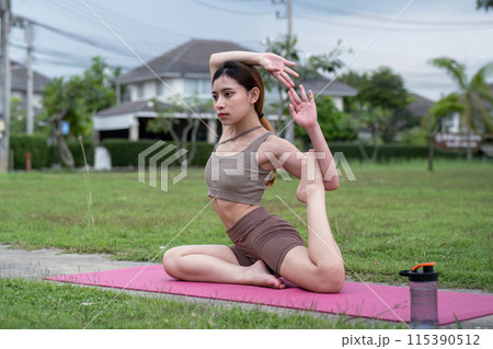 Young Woman Practice Yoga in Park - Healthy Lifestyle, Stretching, and Fitness Outdoors. Serene and Peaceful Exercise Routine on a Yoga Mat in a Green Natural Environment 115390512