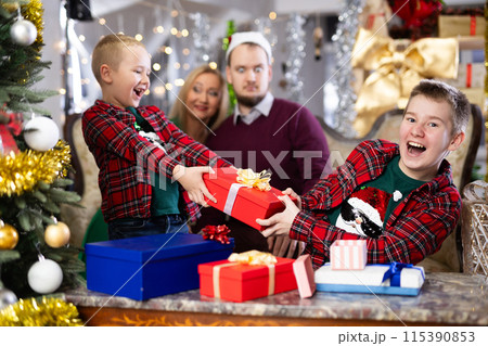 Children and parents give each other gift boxes during Christmas or New Year celebrations at home Children and parents give each other gift boxes during Christmas or New Year celebrations at home 115390853