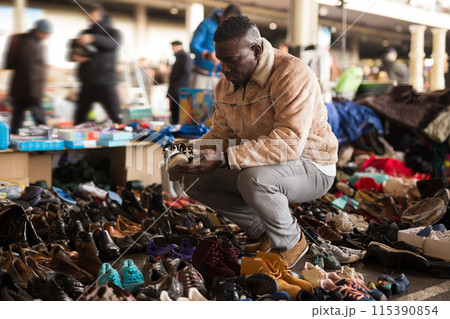 Ordinary african american guy sells sacond hands shoes at flea market Ordinary african american guy sells sacond hands shoes at flea market 115390854