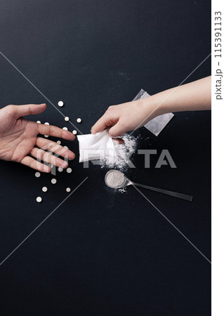 a hand holding a plastic bag containing drugs 115391133