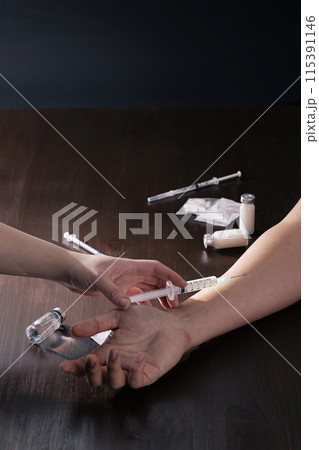 stabbing a needle of a drug filled syringe into the wrist stabbing a needle of a drug filled syringe into the wrist 115391146