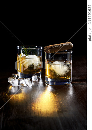 composition of two glasses of cold whiskey and cigar 115391623