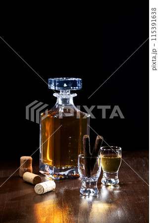 a bottle of liquor and glasses with a black background a bottle of liquor and glasses with a black background 115391638