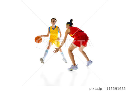 Defense Dynamics. Motivated young women, basketball athletes in yellow and red uniforms in motion, playing isolated on white studio background Defense Dynamics. Motivated young women, basketball athletes in yellow and red uniforms in motion, playing isolated on white studio background 115391683
