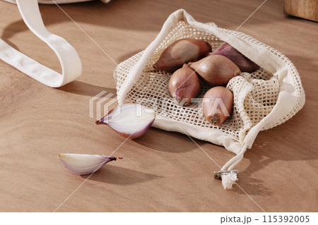 a pile of shallots in a net bag 115392005