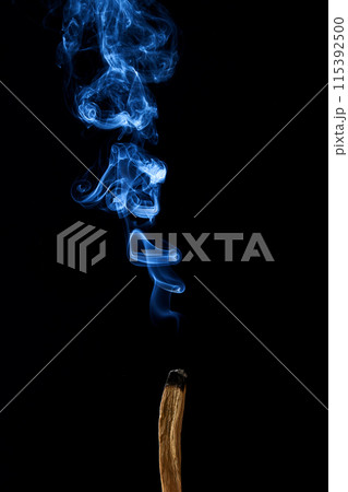 Smudge stick with smoke against a dark background Smudge stick with smoke against a dark background 115392500