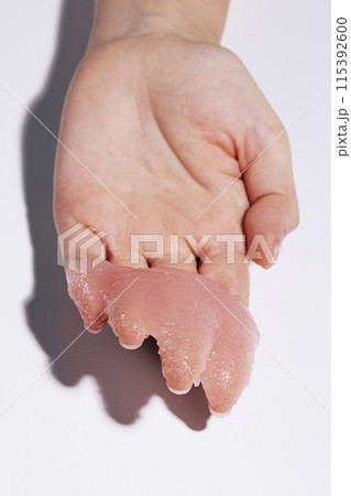 A soft pink scrub on the palm of your hand 115392600