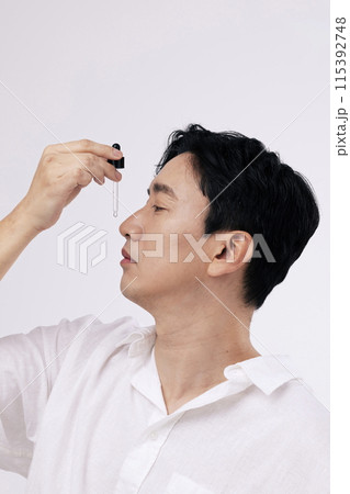 a middle aged man who drops a dropper containing an ampoule into his nose 115392748