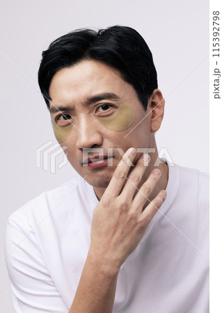 a middle aged man staring straight ahead with eye patches around his eyes 115392798