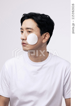 a middle aged man with a circular cotton pad on both cheeks 115392816