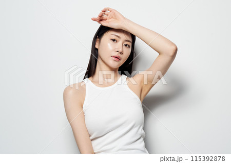Asian woman posing with her hand on her head against a white background Asian woman posing with her hand on her head against a white background 115392878