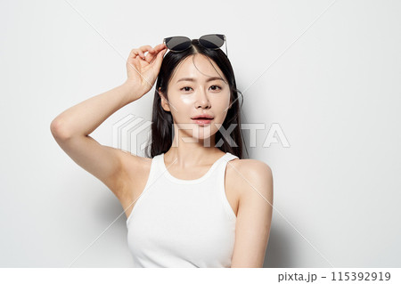 an Asian woman who wears sunglasses on her head with one hand 115392919