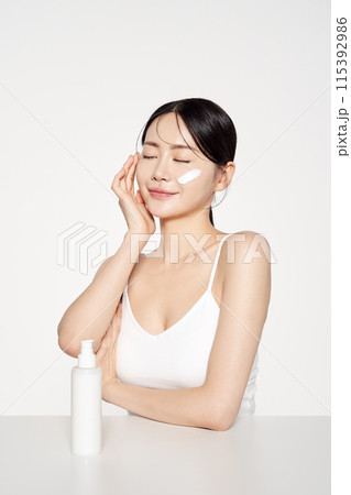 Asian Woman Poses to Apply Cosmetics to Her Face Asian Woman Poses to Apply Cosmetics to Her Face 115392986