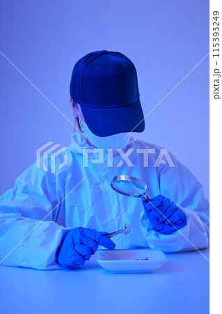 CSI female researcher identifying cigarette butts evidence as magnifying at crime and incident sites with blue lights CSI female researcher identifying cigarette butts evidence as magnifying at crime and incident sites with blue lights 115393249