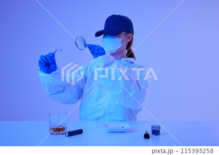 CSI female researcher identifying cigarette butts evidence as magnifying at crime and incident sites with blue lights CSI female researcher identifying cigarette butts evidence as magnifying at crime and incident sites with blue lights 115393258